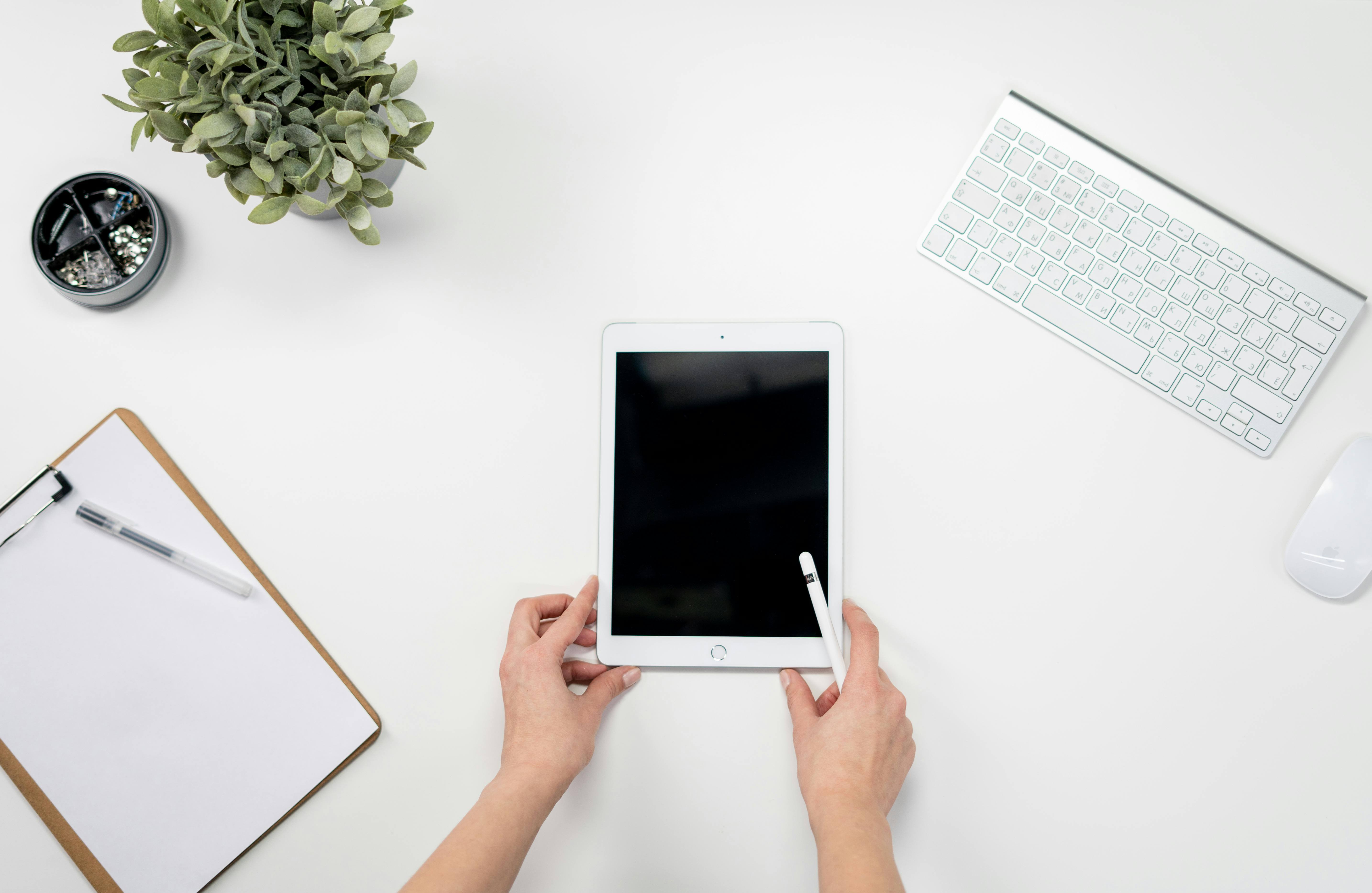 Person Holding White Ipad With Apple Keyboard