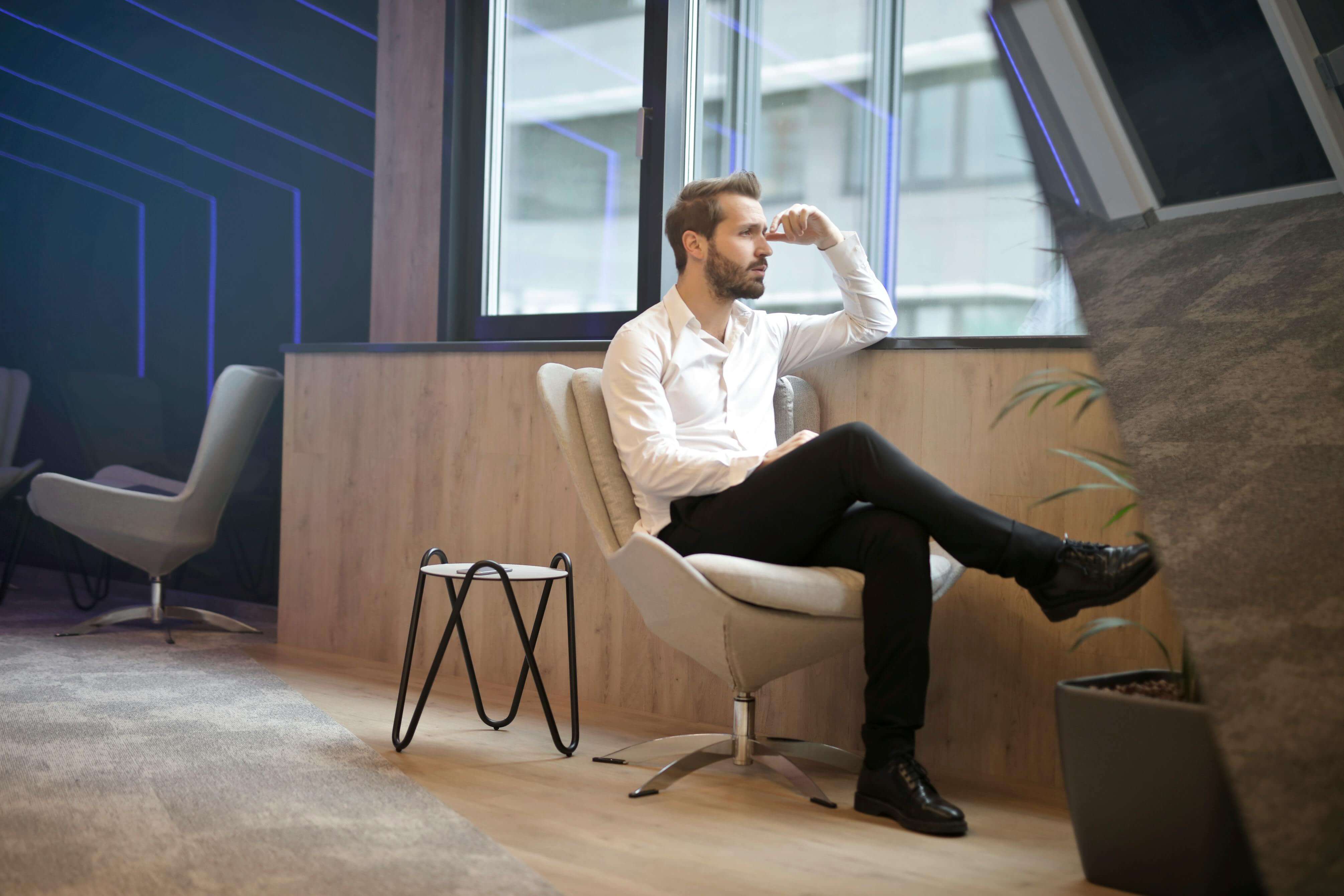 Photo of a Man Sitting Near the Window