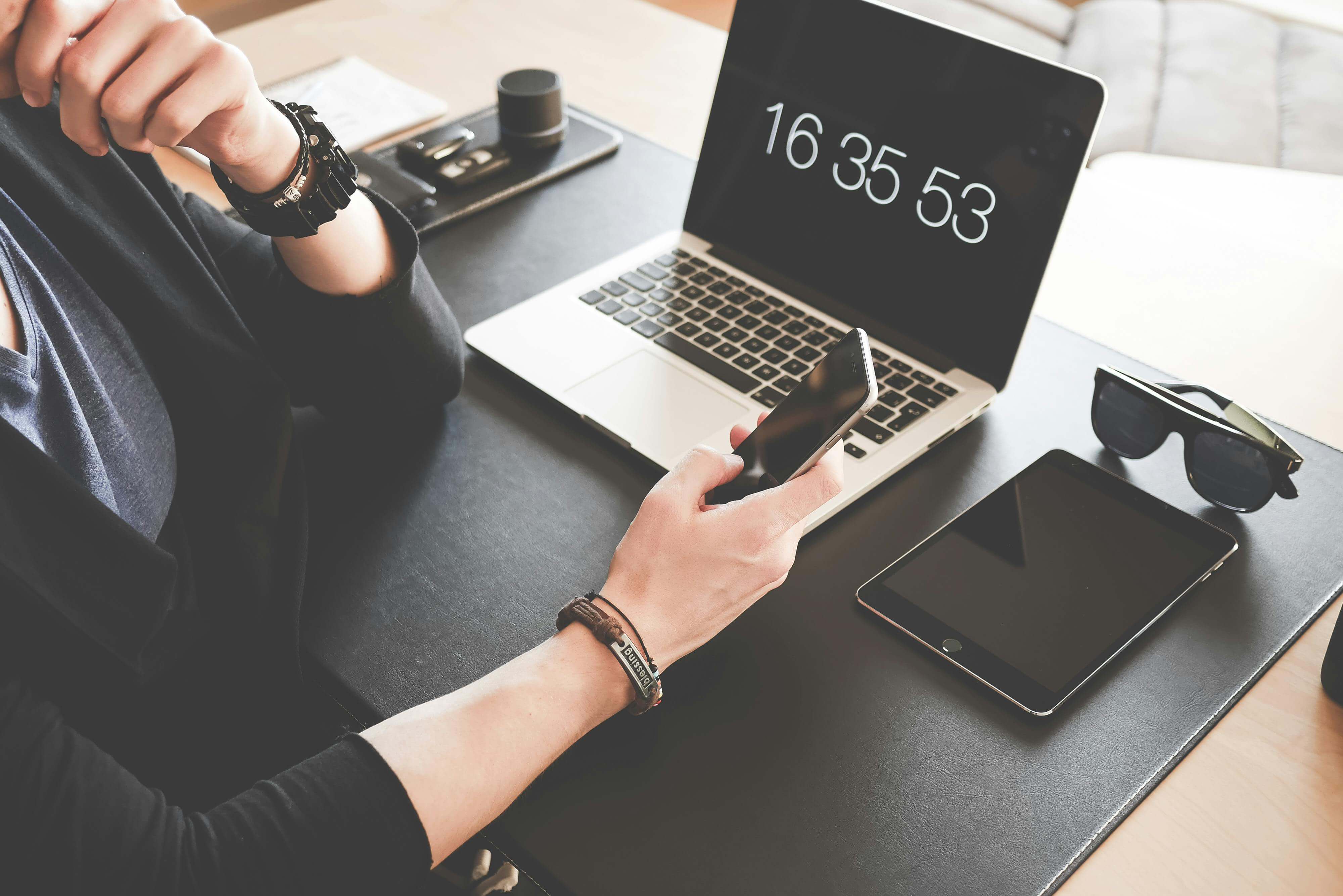 Woman Using a Smartphone While Fronting a Macbook Pro and Black Ipad