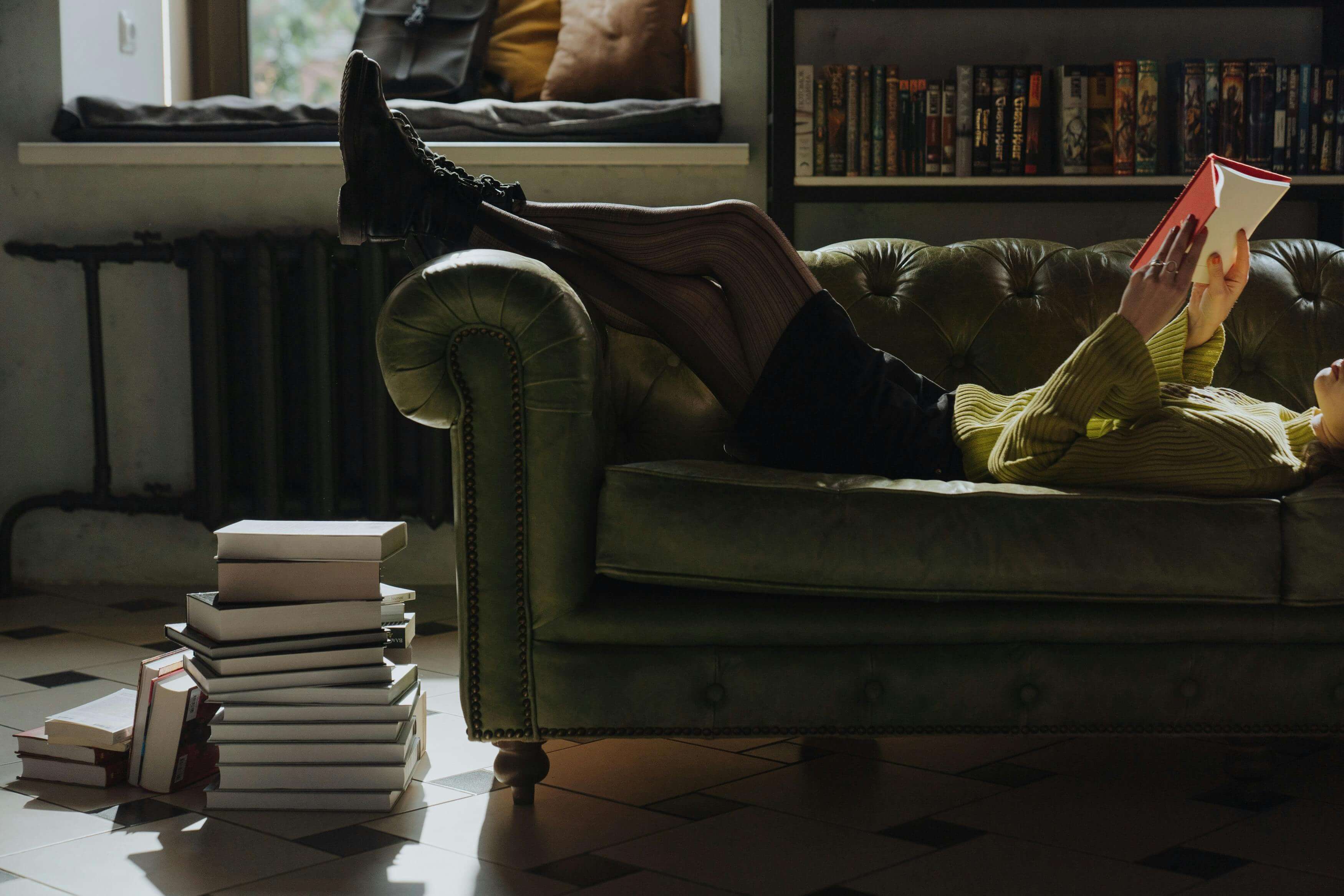 Person Lying Down on Sofa Reading a Book