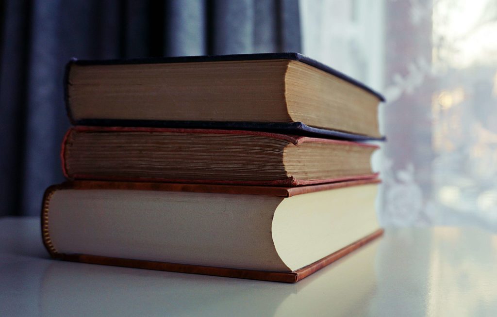 Three Piled Books on White Wooden Table