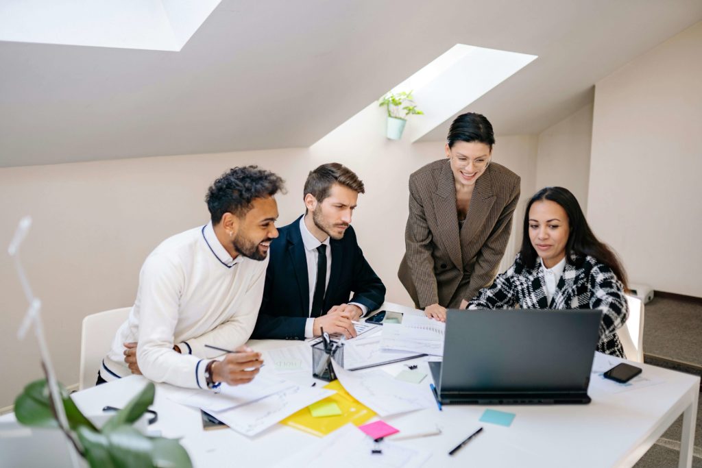 Group of Men and Women Looking at a Laptop and Working Together