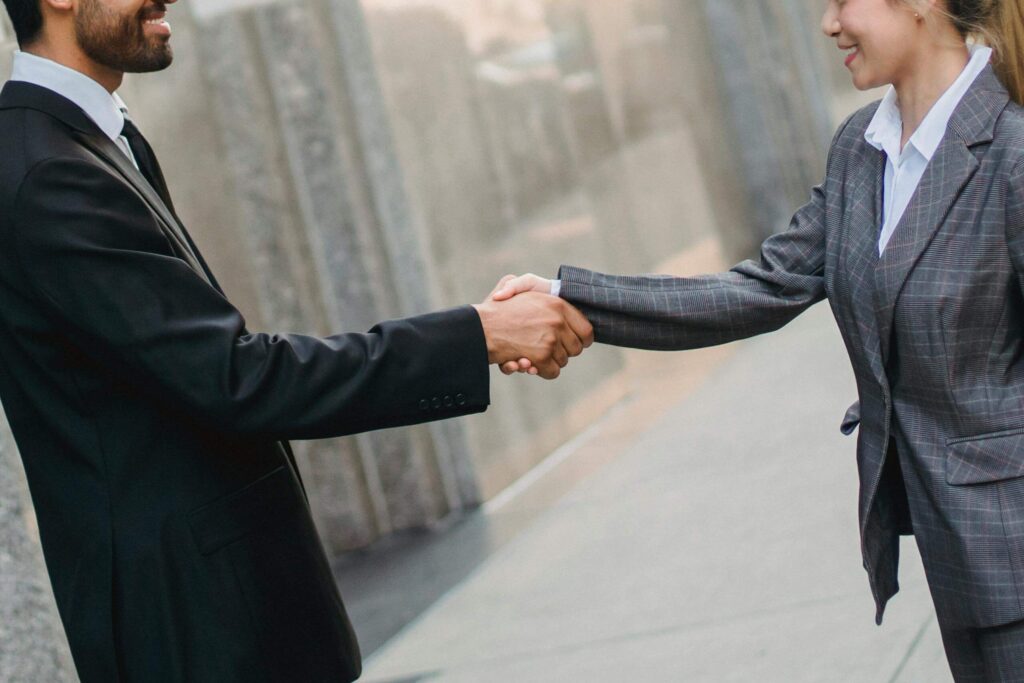 Man in Black Suit Shaking a Woman's Hand